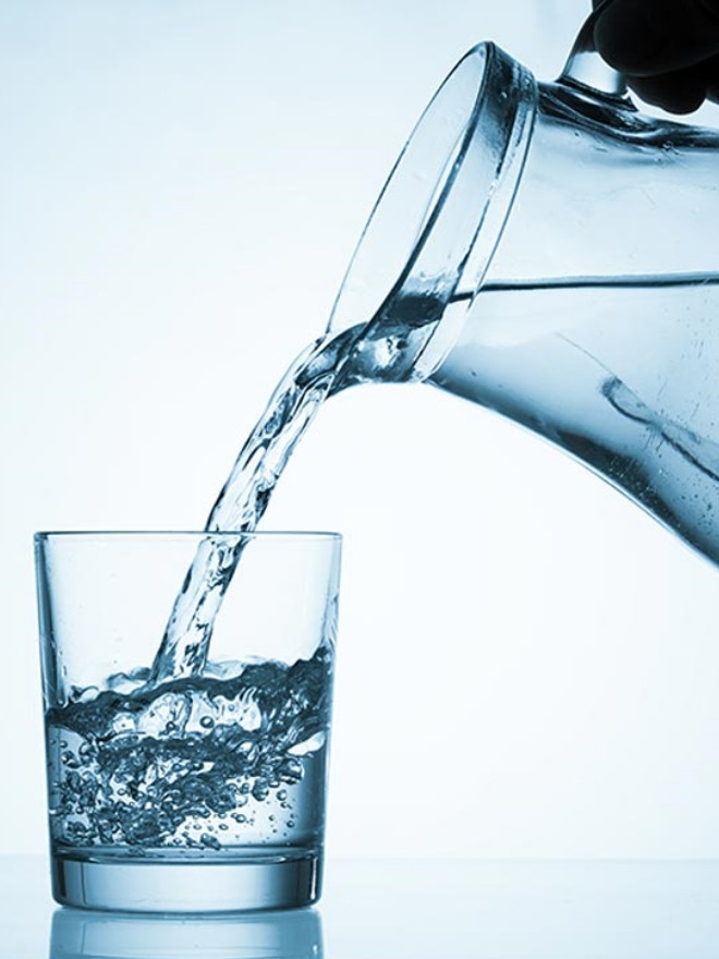 Ein Mann gießt das Wasser in ein Glas.