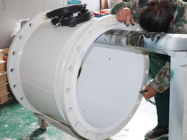 Un trabajador está puliendo el material de revestimiento de un medidor de flujo electromagnético