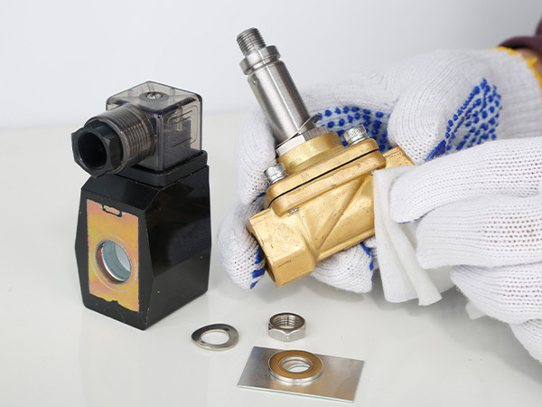 A worker is disassembling the components of the solenoid valve for maintenance.